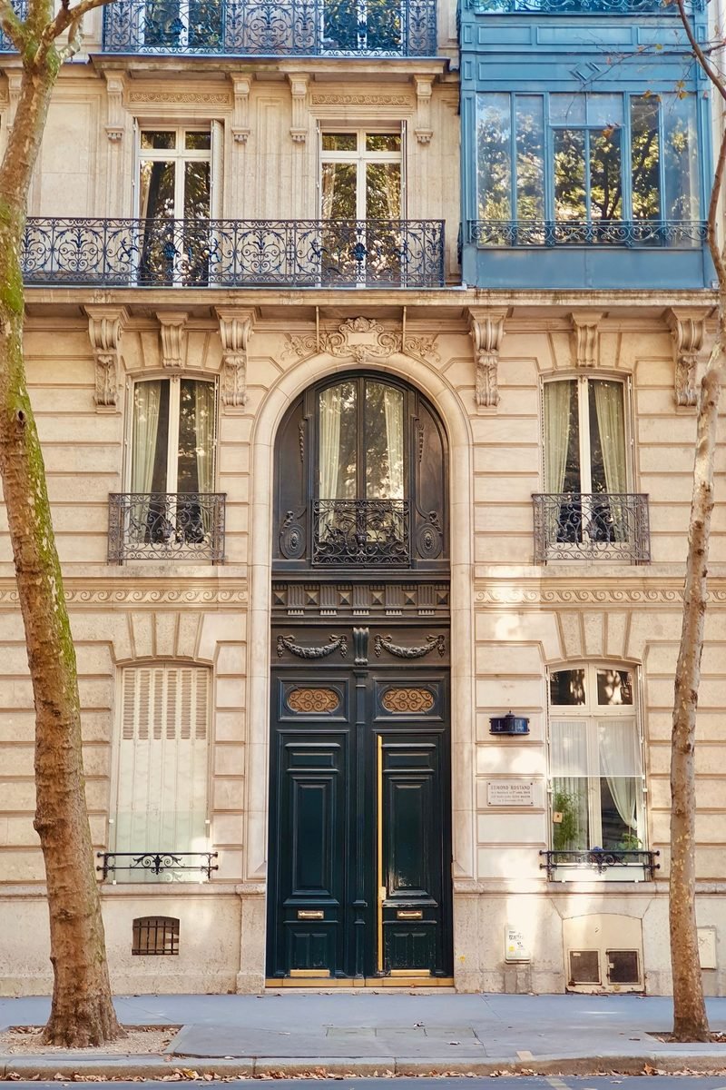 Porte cochère d'un immeuble haussmannien à Paris, façade en pierre de taille et balcons en fer forgé