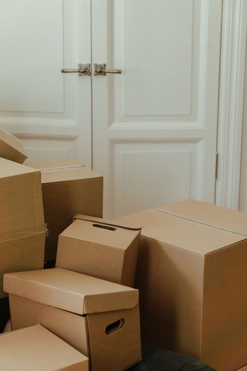 Cartons de déménagement devant une porte double moulurée, départ d'un appartement lors d'une vente immobilière